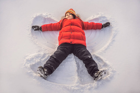 一个男孩,躺在雪地上,用他的胳膊和腿,情绪,笑声,做一个雪天使照片
