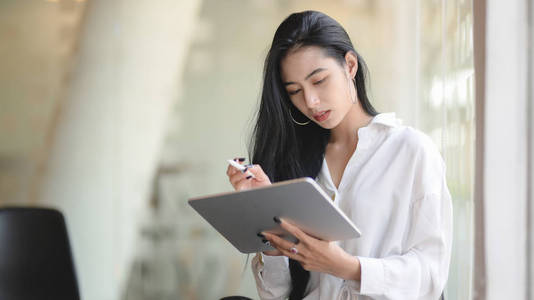 Portrait of successful asian businesswoman using digital tablet 