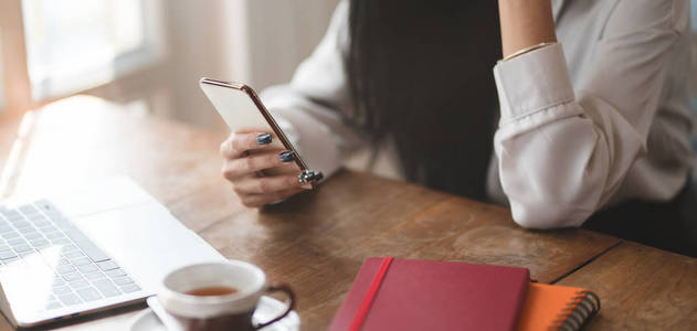 Cropped shot of businesswoman using smartphone while working on 