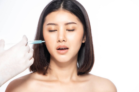 Asain young woman gets injection of botox in her lips. Woman in 