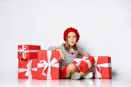 快乐可爱的小女孩拿着一个红色的礼品盒，盒子的背景是白色的丝带