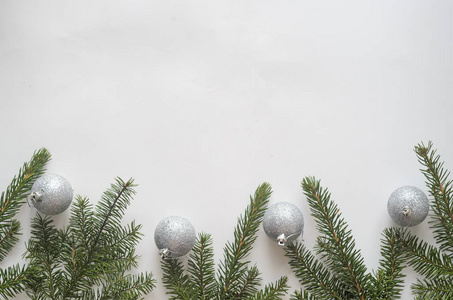 圣诞节还是新年组成。顶部视图中，白色背景上有四个银色的球和圣诞树树枝，顶部是复制空间。