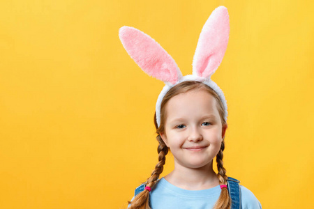 可爱的小女孩长着兔子耳朵。黄色背景的儿童特写镜头