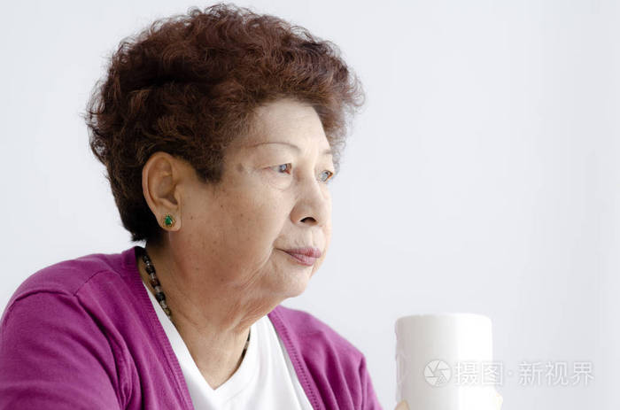 亚洲老年妇女在窗边喝杯热茶照片-正版商用图片26837w-摄图新视界