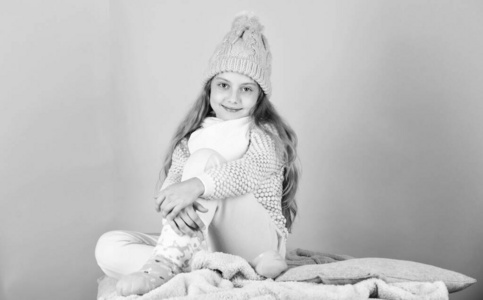 儿童长发保暖羊毛帽享受温暖。保暖衣概念。保持温暖舒适。温暖的配饰，让你在这个冬天感到舒适。小女孩戴针织帽子放松粉红色背景