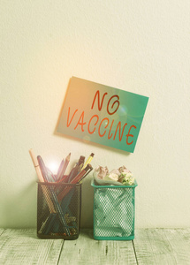 显示没有疫苗的文字标志。概念照片不提供一种或几种疾病的免疫力墙上有两个铅笔壶钢笔铅笔记号笔废纸。
