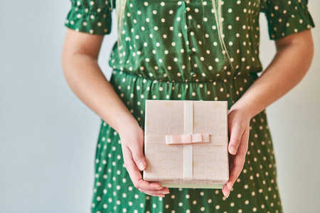 A girl holds a gift box on a white background. 