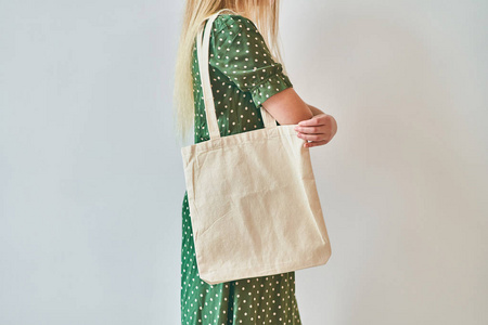 一个女孩拿着空白的棉质环保手提包，设计模型。