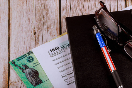 会计办公室办公桌美国个人所得税申报表1040，带眼镜和钢笔以及个人退款支票