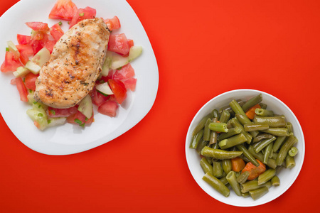 Grilled chicken breast with tomato salad, cucumbers and onions. 