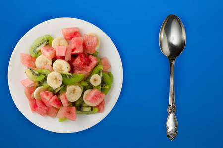 fresh fruit salad on white plate on background.