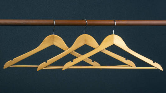Empty wooden clothes hanger hanging on a dark background. Access