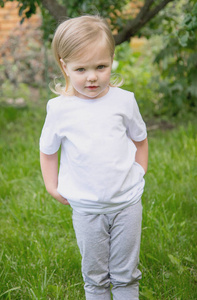 一个三岁的小女孩穿着白色t恤在花园模型里