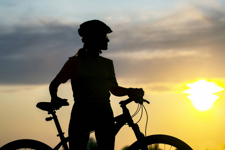 一个骑自行车的女孩的剪影，背景是一辆自行车