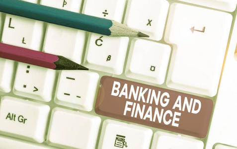 显示银行和金融的文字标志。概念照片会计和实体股票货币利益白色电脑键盘与空白笔记纸上方白色背景键复制空间。