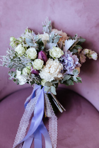 盛开着一束粉红色的牡丹和紫丁香蔷薇花，绿叶插在玻璃花瓶里。