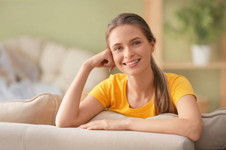 快乐的年轻女人坐在家里的沙发上