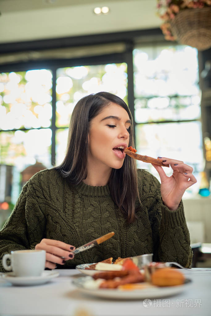 早上坐在餐厅吃早餐的迷人的黑发女人