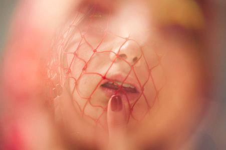 艺术女孩的头在脸前织了一张粉红色的网，被镜头模糊了