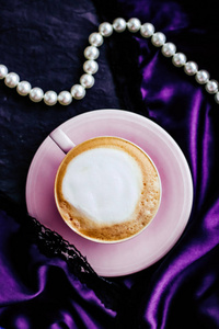 Cup of cappuccino for breakfast with satin and pearls jewellery 