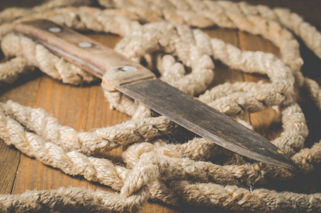 Knife with wooden handle and rope on old wooden background. Old 