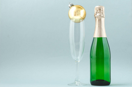 一瓶香槟和圣诞玩具放在一个蓝色的ba上的玻璃器皿里