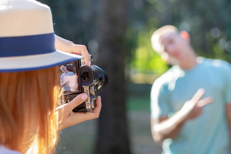 Young teenage couple taking pictures of one another outdoors in 