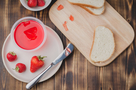 Strawberry jam. Bread and strawberry jam on a wooden table with 