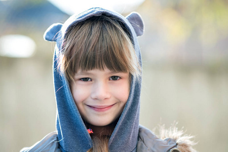 秋天户外穿着温暖衣服的快乐小女孩的肖像。