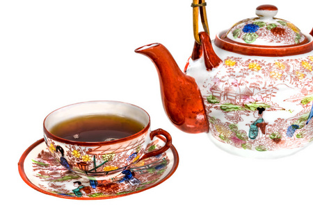 装满茶的茶杯和彩瓷茶壶