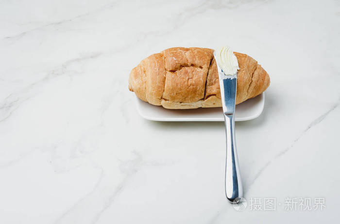 羊角面包和黄油刀放在一张白色的石桌上。法语