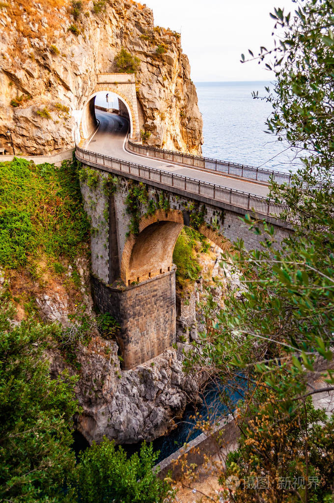 的高岩石悬崖之间建造的fiordodifurore弧形桥汽车在桥上行驶小船漂浮