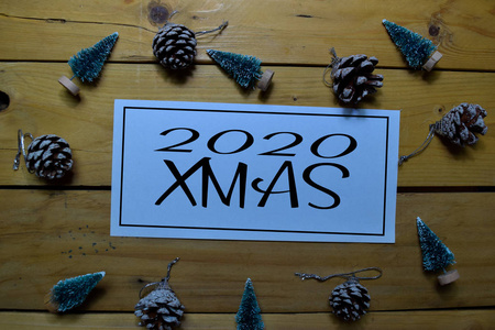 2020年圣诞节写在白纸上，背景是木制的。圣诞装饰的框架。