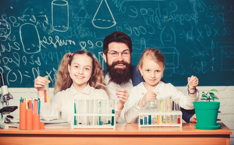 学校生物实验。给孩子们讲解生物学。如何激发孩子们的学习兴趣。有趣的生物课。留着胡子的老师在生物教室里用显微镜和试管工作