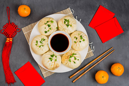 在灰色混凝土背景上用饺子橘子酱油筷子红包装饰春节。2020年春节快乐