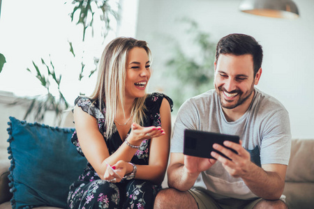 Smiling happy couple with tablet pc computer and credit or bank 