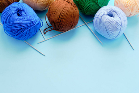 蓝色背景上有鲜艳的彩色纱线。阿米古鲁米玩具制造概念，手工艺，针织，霍比娃娃。