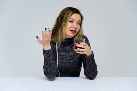 一个坐在桌边的女人的画像，头发卷曲，情绪激动，穿着灰色连衣裙，白色背景，手里拿着一杯威士忌。女性酗酒观念。