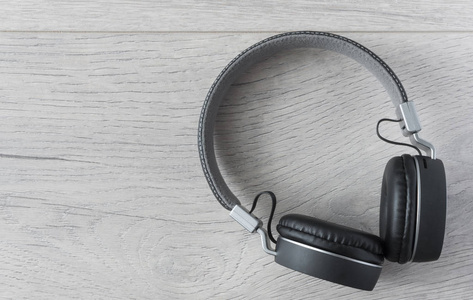 Black headphones lay discarded to the right on the wooden floor 