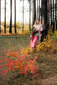 Girl walking in the autumn forest. A large beautiful bouquet of 