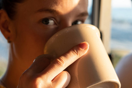 女孩手里拿着一个杯子喝了一杯。闭合。