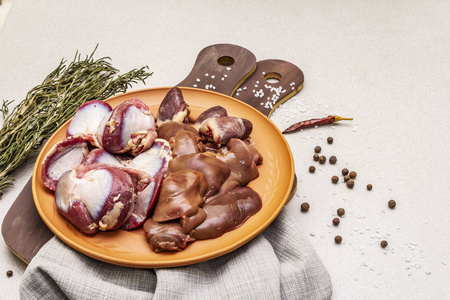 鲜生鸭内脏:心,肝,胃.干香料,盐,辣椒.木制切割板,石混凝土背景照片