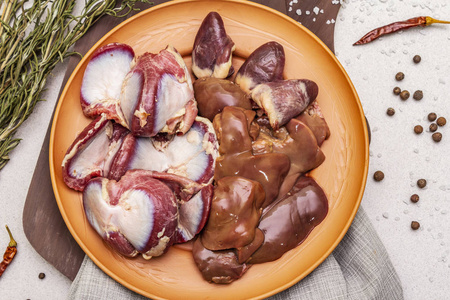 鲜生鸭内脏:心,肝,胃.干香料,盐,辣椒.木制切割板,石混凝土背景照片