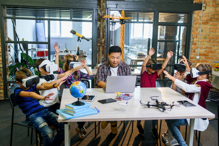 一群小学生在电脑编码课上使用虚拟现实眼镜。