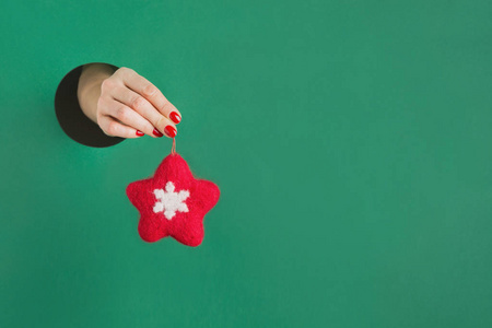 女手捧着红星穿过绿纸上的圆孔。手工玩具。圣诞装饰。
