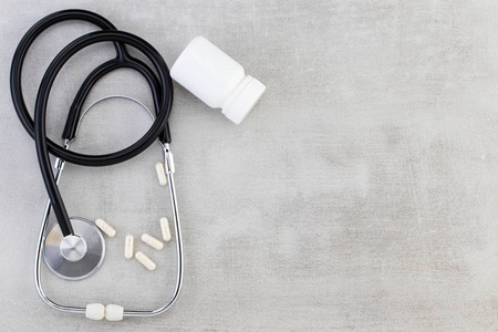  Stethoscope, pills, tablets and capsules on a gray background .