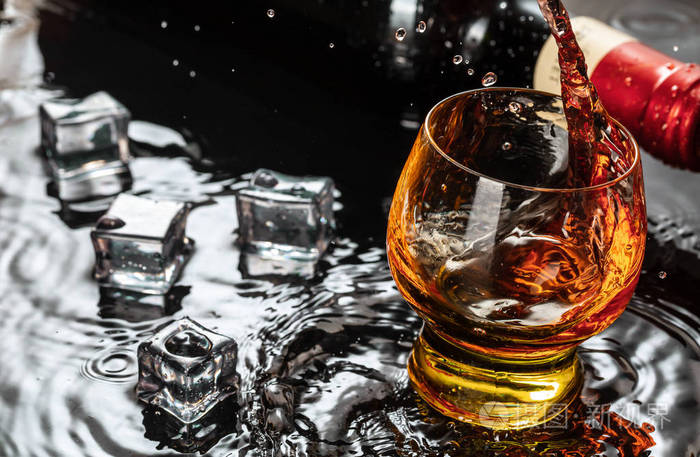 一瓶红酒加酒杯水溅落在黑色的倒影上