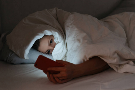 晚上躺在床上盯着手机的年轻女人照片