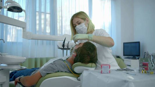 戴口罩的牙医检查病人的牙齿