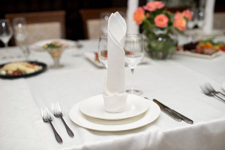 白色的餐巾很好地叠在盘子上，为庆祝宴会服务。